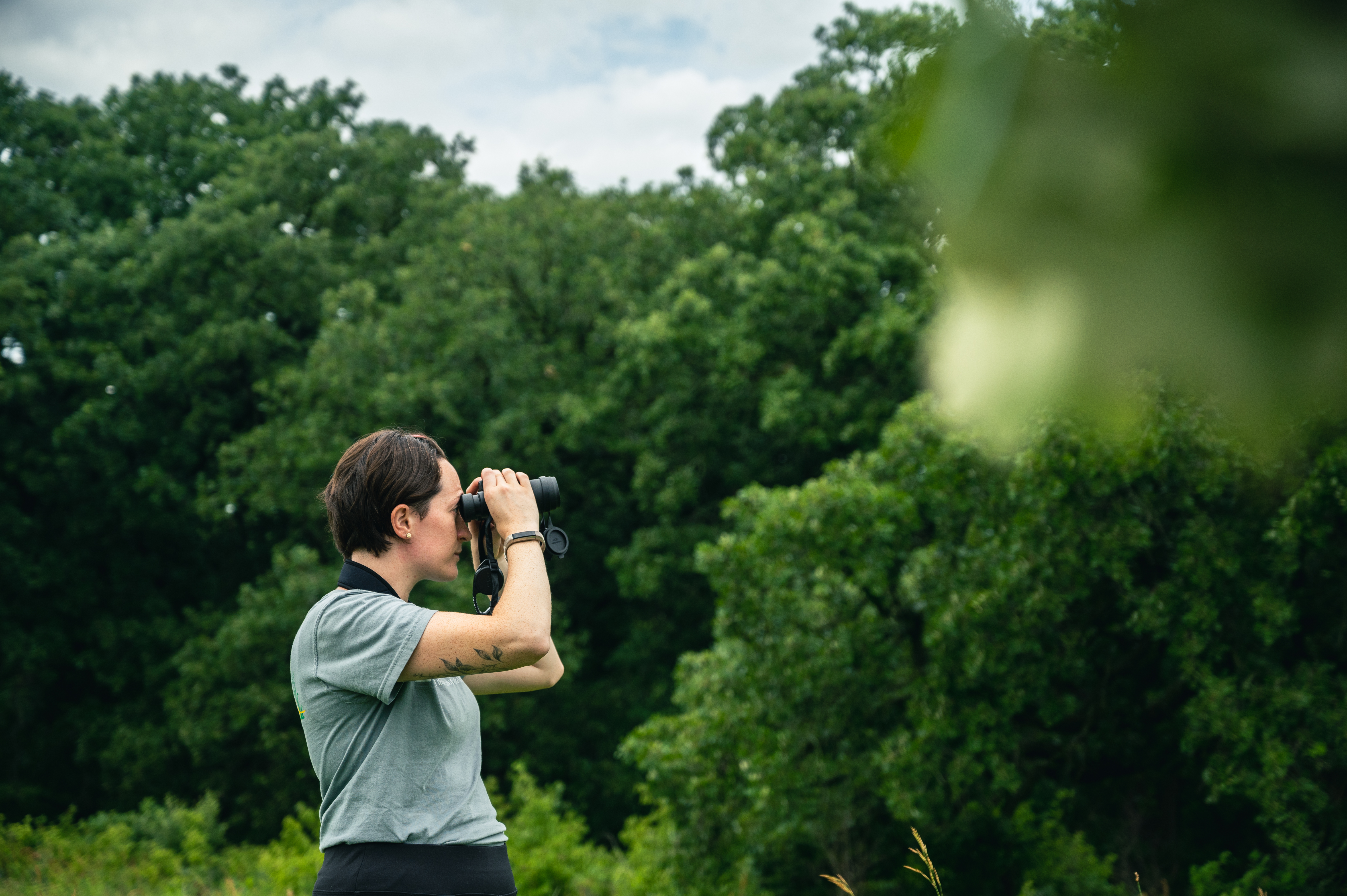 PhD student Allison Barg looks through binoculars to identify a bird in the field