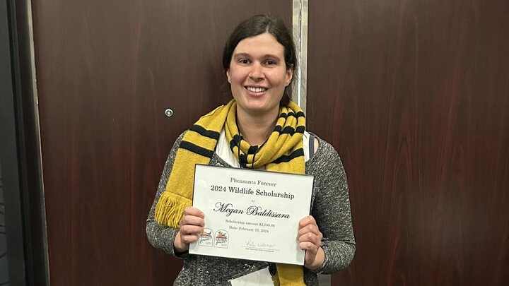 Megan Baldissara holds up her scholarship certificate