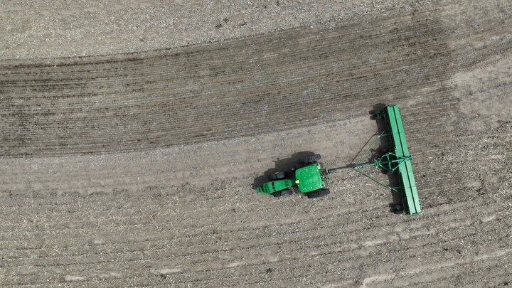 aerial shot of a tractor planting a prairie strip in a fallow field