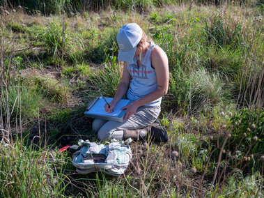 Graduate student Grace fills out a data sheet in the field