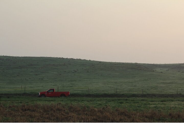 A red pickup truck parked along a field